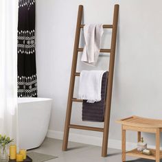 a bathroom with a wooden ladder next to a bathtub and towel rack on the wall