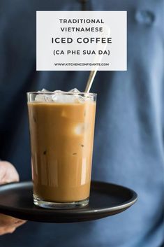 a person holding a plate with a drink on it and a sign that says traditional vietnamese iced coffee ca phe su dai