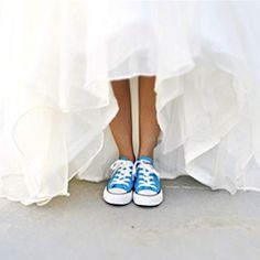 a woman in blue and white tennis shoes standing on the ground with her legs crossed