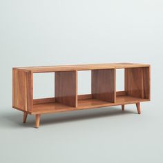 a wooden shelf with three compartments on one side and two legs, in front of a gray background