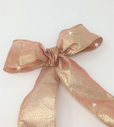 a pink and gold bow with some sparkles on it's side, against a white background