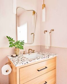 a bathroom with pink tile and gold fixtures, including a vanity mirror above the sink