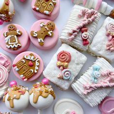 many decorated cookies and pastries are on the white tablecloth with pink trimmings