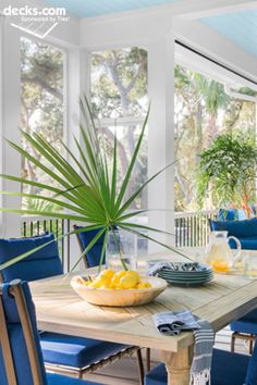 a dining room table with blue chairs and a bowl of lemons on the table