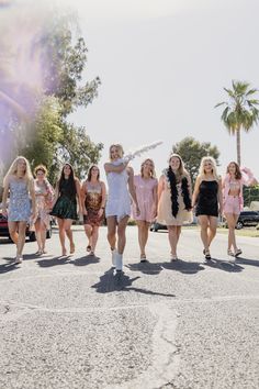 a group of women walking across a parking lot next to each other on a sunny day