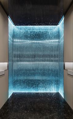 a large shower head in the middle of a room with blue lights on it's walls