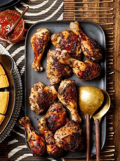 grilled chicken on a platter with two serving spoons next to the tray