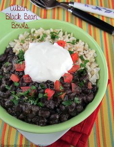 a green bowl filled with black beans and rice topped with sour cream on the top