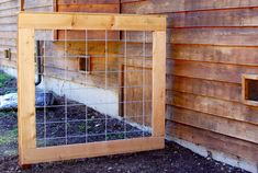 a wooden frame with a window on the side of a building next to a fence