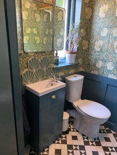 a bathroom with a toilet, sink and mirror in it's corner next to a tiled floor