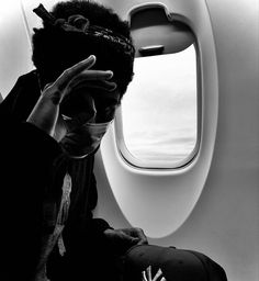 a black and white photo of a person sitting on an airplane with his head in his hands