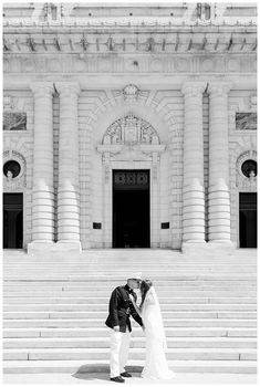 a bride and groom kissing in front of an old building with steps leading up to it