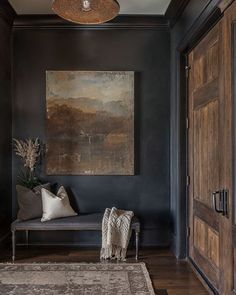 a large painting hangs on the wall next to a chair and rug in a dark room