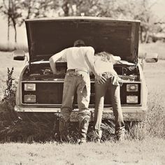 two people are standing in the trunk of an old car with their head on another man's back