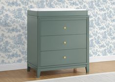 a green chest of drawers in a room with blue wallpaper