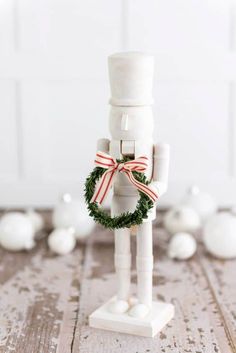 a white wooden figurine with a wreath on it