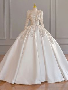 a white wedding dress with long sleeves and lace on the skirt is displayed in front of a