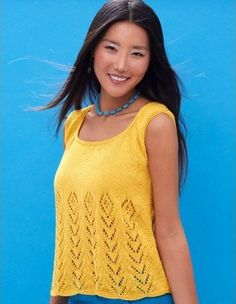 a beautiful young woman standing in front of a blue wall wearing a yellow top and jeans