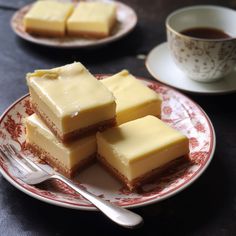 four pieces of cake on a plate with a cup of coffee and saucer in the background