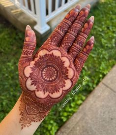 a person's hand with henna on it and green grass in the background