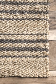 a close up view of the top of a rug on a wooden floor with grey and white stripes