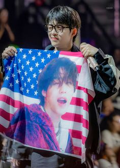 a young man holding up an american flag with a photo of him in the background