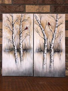 two paintings of trees with birds on them in front of a brick wall and wood floor