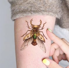 a woman's arm with a tattoo of a bug on it