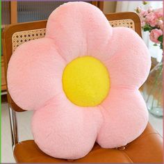 a pink flower pillow sitting on top of a brown chair