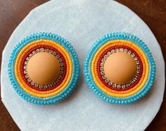 an egg is sitting in the center of two beaded earrings on top of a white plate