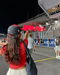 a woman taking a photo with her cell phone in front of an empty race track