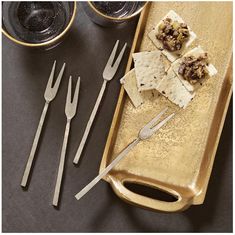 silverware and crackers on a gold tray with utensils next to them