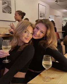 two women sitting at a table with wine glasses