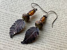 * Autumn! I pulled in several shades of amber in these beauties by pairing a beautiful amber Czech glass bead with the perfect polymer clay branch bead by Humblebeads. I then hammered leaf veins on a Vintaj blank component and then added several shades of patina.  * Earrings measure 3 inches  * Designed in Poestenkill NY * NOTE: Wearing in water or to the gym is not recommended  * NOTE:  As with most jewelry , do not force an adjustment if an earring becomes mis-aligned or stuck. Just give a gentle tug or wiggle and it will straighten out easily. Nickel-free Brown Beaded Earrings With Czech Glass, Nickel-free Brown Czech Glass Beaded Earrings, Handmade Amber Earrings In Czech Glass, Handmade Brown Leaf-shaped Jewelry, Nature-inspired Brown Earrings For Jewelry Making, Nickel-free Brown Earrings With Czech Glass, Nickel Free Brown Earrings With Czech Glass, Nickel-free Brown Czech Glass Earrings, Nickel-free Amber Czech Glass Earrings