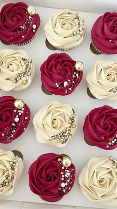 twelve cupcakes in a white box decorated with red and cream frosting roses