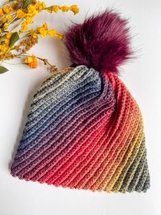 a multicolored knitted hat with a pom - pom on top