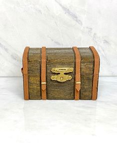 an old fashioned wooden chest sitting on top of a white counter next to a marble wall