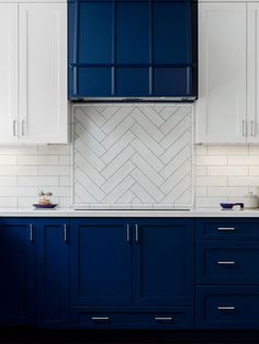 a kitchen with blue cabinets and white subway tile backsplash, herringbone pattern