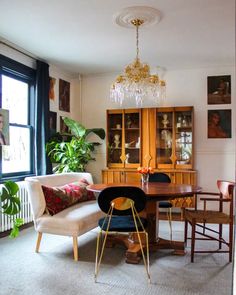 a living room filled with furniture and a chandelier hanging from the ceiling next to a window