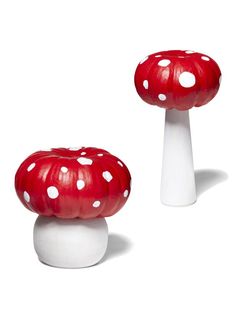 two red and white mushrooms sitting next to each other on top of a white table