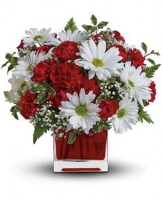 a red vase filled with white and red flowers