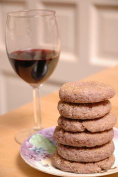 a stack of cookies sitting on top of a plate next to a glass of wine