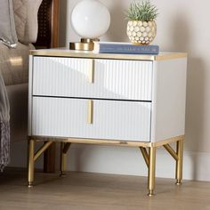 a white and gold nightstand with a plant on top