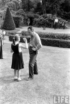 an old black and white photo of two people in a garden, one holding the other's hand