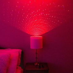 a bed room with a lamp and a red light in the ceiling above it on top of a night stand