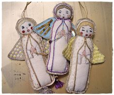 three handmade christmas ornaments hanging on a wooden wall, one with an angel and the other with a baby jesus