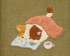 a close up of a piece of cloth with a cat on it and a cup