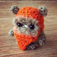 a small stuffed animal wearing a knitted orange and gray hat on top of a wooden table