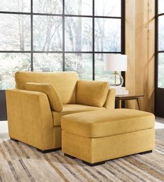 a yellow chair and ottoman in front of a large window