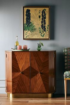 a wooden cabinet sitting on top of a hard wood floor next to a green chair